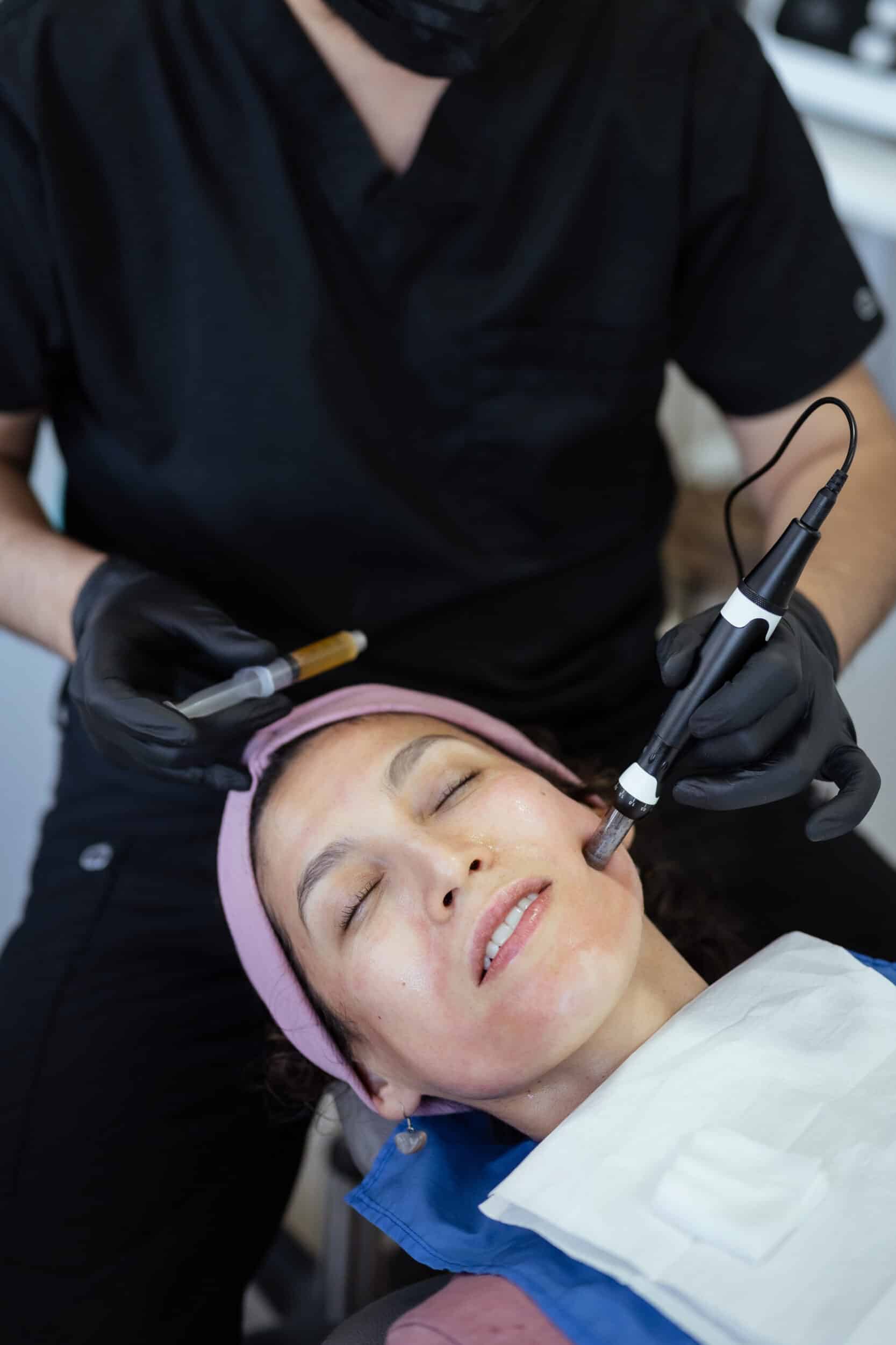 Beautician applying platelet rich plasma with dermapen on woman's face